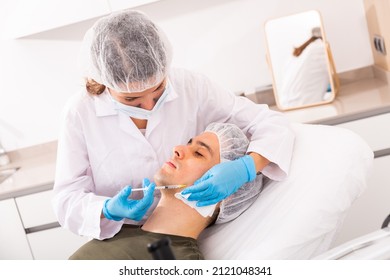 Focused Woman Cosmetologist Giving Beauty Injections For Face Skin Tightening For Male Client In Aesthetic Medicine Office