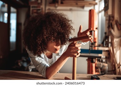 Focused woman crafting in a woodworking studio - Powered by Shutterstock