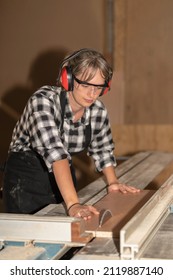 Focused Woman Cutting Wood At A Carpentry Workshop