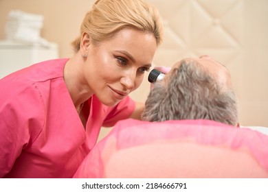 Focused woman dermatologist-oncologist conducts examination with the help of dermatoscope