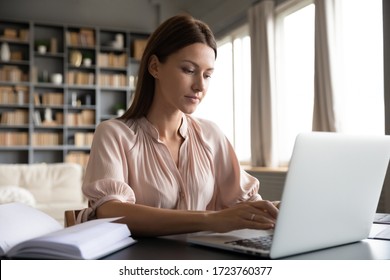 Focused woman journalist freelancer working online on laptop, sitting at desk at home, looking at screen, typing, serious young female writing blog or chatting with friends in social network - Shutterstock ID 1723760377