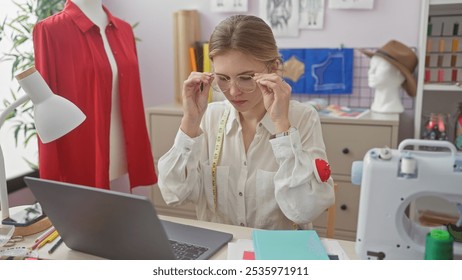 A focused woman tailor adjusts her glasses in a colorful fashion atelier surrounded by sewing equipment and mannequins. - Powered by Shutterstock