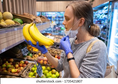 Focused Woman Taking Off Face Mask While Choosing Fruits In Grocery Store. Customer In Supermarket. Side View. Shopping During Epidemic Concept