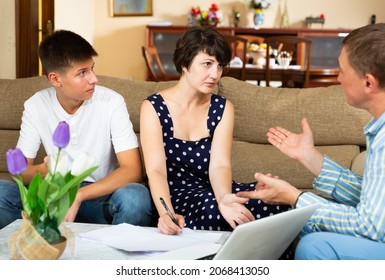 Focused Woman With Teenage Son Discussing Apartment Rental Agreement With Landlord, Signing Papers On Sofa At Home