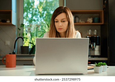 Focused woman typing on laptop at home office desk. Millennial freelance woman working remotely. Concept of online distant work - Powered by Shutterstock