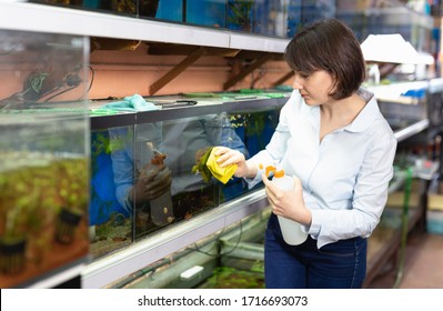 Focused Woman Working In Pet Store, Washing Glass Of Aquariums

