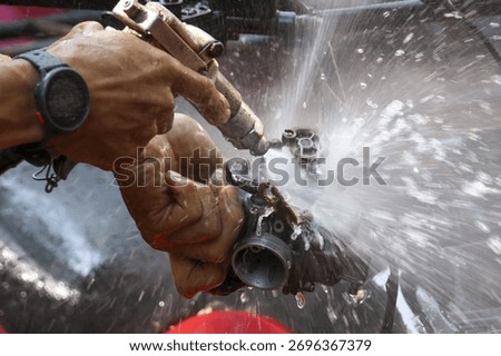 Focused worker performs industrial maintenance, using high pressure water gun for cleaning metal part. powerful spray removes dirt with intense force and precision