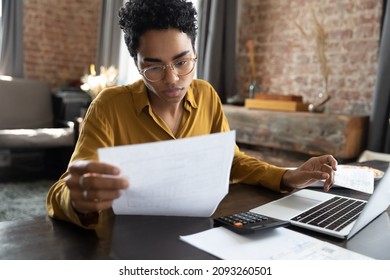 Mujeres afroamericanas enfocadas en gafas mirando a través de documentos en papel, manejando asuntos de negocios, resumiendo impuestos, planificando inversiones futuras, contando solo en la oficina del hogar.