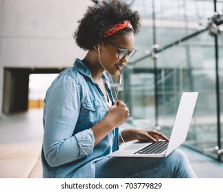 Focused Young African Female College Student Working On A Laptop While Sitting On A Bench On Campus Preparing For An Exam