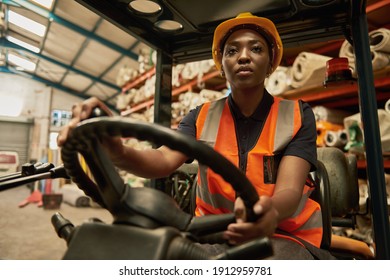 Focused young African female forklift operator moving boxes around a textile warehouse - Powered by Shutterstock