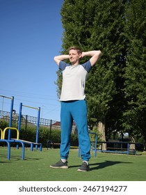 A focused young athlete dynamically performing warm-up drills and stretches outdoors. Clad in athletic gear, he meticulously prepares body for the physical demands ahead through a regimented routine