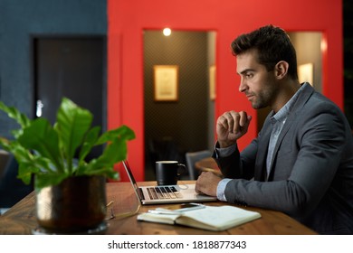 Focused young businessman working on a laptop while sitting alone at his desk in a quiet office after hours - Shutterstock ID 1818877343