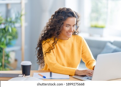 Focused young businesswoman studying online, watching webinar, podcast on laptop, making notes, sitting at work desk. E-learning concept.