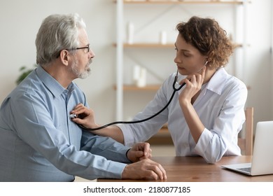 Focused young female cardiologist or general practitioner in white coat listening heartbeat or elderly senior male patient at checkup meeting, preventing cardiovascular disease, healthcare concept. - Shutterstock ID 2180877185