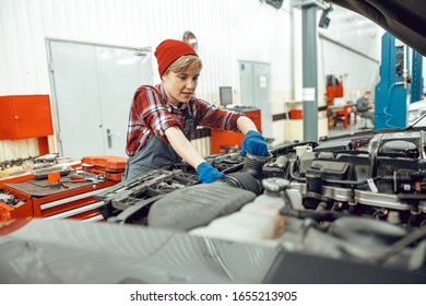 Focused Young Female Mechanic Inspecting A Car Coolant Hose