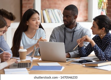 Focused Young Indian Girl And Black Guy Listening To Groupmate. Asian Female Student Explaining School Project Details Or Sharing Ideas With College Friends. Group Of Diverse Teens Working Together.