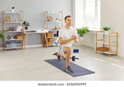 Focused young man in activewear having a fitness workout at home, standing on a yoga mat in the living room, and doing a forward lunge exercise. Sport, wellness, physical activity concept - Powered by Shutterstock