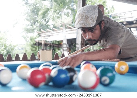 Focused young man lines up his shot on the billiards table, showcasing precision and skill. Promotion of local billiards tournament. Concept of billiards sport, gambling, hobby, leisure, game