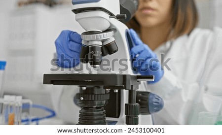Focused young scientist examining samples using a microscope in a laboratory environment, portraying modern scientific research.