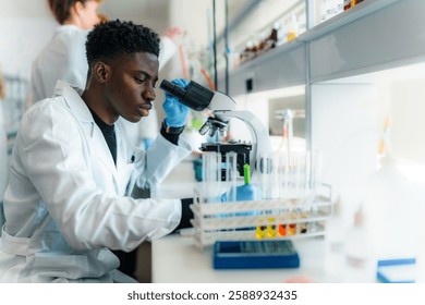 Focused young scientist using microscope, analyzing samples in test tubes, conducting research in a modern laboratory environment with advanced equipment and innovative technology