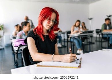 Focused young student taking notes from books for her study. College student sitting at desk and studying.