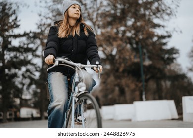 Focused young woman cycling through a scenic park with autumn vibes, promoting health and eco-friendly transportation. - Powered by Shutterstock