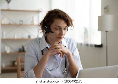 Focused Young Woman Doctor Wearing Headset With Microphone Looking At Laptop Screen, Working Online Consulting Patient, Serious Physician Nurse Gp Making Video Call, Telemedicine Concept