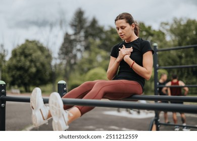 Focused young woman performing a leg lift exercise on outdoor gym equipment in a green park setting, demonstrating commitment to fitness. - Powered by Shutterstock