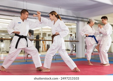 Focused young woman in traditional white kimono sparring with male partner during martial arts training in gym.. - Powered by Shutterstock