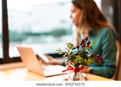 Focused young woman works on her laptop in a cozy, vintage café, with a vibrant decorative plant in the foreground