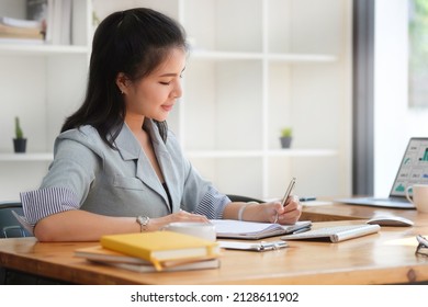 Focuses Young Female Financial Adviser Checking Financial Report At Office Desk.