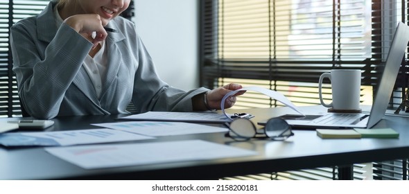 Focuses Young Female Financial Adviser Checking Financial Report At Office Desk.