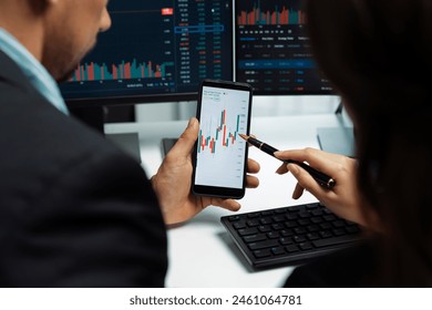 Focusing on phone with discussing dynamic stock market in two business traders online website compare with pc screens in real time currency rate investment on risk data at modern office. Postulate. - Powered by Shutterstock