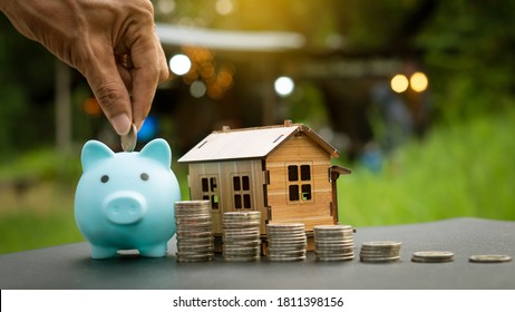 Focusing on the piggy bank, the man puts coins into the piggy bank, where the coin and house are personal finance backgrounds, homeownership savings plans, and house name savings ideas.