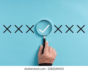 Focusing on the right choice concept. Hand holds magnifying glass focusing on the checkmark or tick right symbol next to wrong cross icons. - Shutterstock ID 2282269653