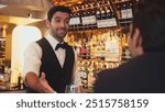 Focusing on smiling smart bartender preparing drinks at luxurious bar while engaging lively conversation with VIP customer at vibrant warm lighting atmosphere bottle bar and pub background. Vinosity.