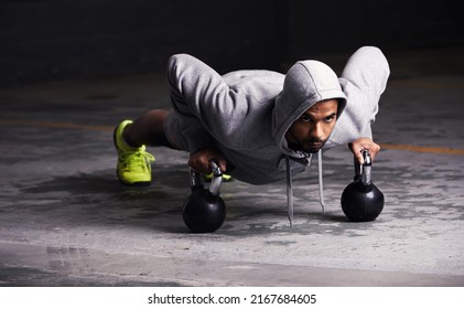 Focussed on his workout. Shot of a young man doing push-ups with kettle bell weights. - Powered by Shutterstock