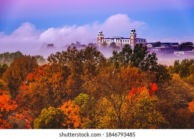 Fog blankets the fall foliage of the valley in front of a historical building in Fayetteville, Arkansas, just before sunrise.