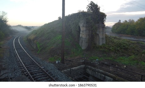 Fog Covered Train Tracks With Remnants Of A Train Bridge On Overcast Morning In The Deep South