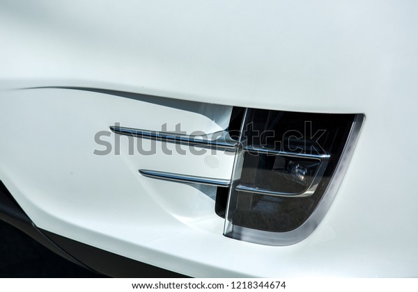 Fog light installed in the lower part of the\
bumper of a white car, a flashlight of additional lighting with a\
pick-up and chrome inserts.