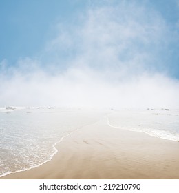 Fog And Mist Hovering On The Ocean Horizon With Gentle Waves Overlapping In The Foreground.