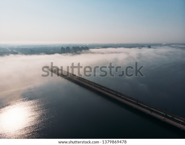 Fog or\
mist over  river bridge with car traffic in city, aerial panoramic\
view, morning haze and cityscape,\
toned