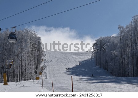 Fog on the Balkan mountain in Serbia, Europe. Ski slope, cable car and some people skiing.