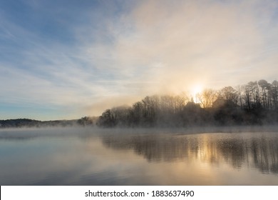 Fog rises on the water of Lake Lanier in Georgia at sunrise under a blue and orange sky; landscape