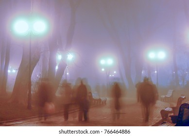 foggy alley of the evening autumn park with burning lanterns and blurred silhouettes of people walking - Shutterstock ID 766464886