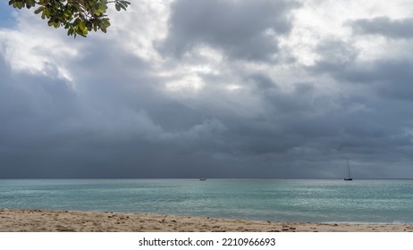 Foggy cloudy day on a tropical beach. Yachts in the distance on the turquoise ocean. Footprints in the sand. A green branch against a background of dense clouds. Seychelles. Mahe. Beau Vallon - Shutterstock ID 2210966693
