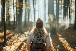 Foggy Cold Morning Weather In Autumn. Woman With Backpack And Knit Hat Hiking In Forest At Fall Season