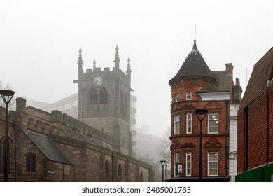 A foggy day in Derby, United Kingdom, highlighting the city's historical architecture with a church clock tower and classic redbrick buildings. - Powered by Shutterstock