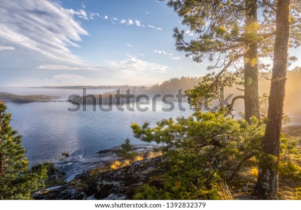 北の自然の霧の深い風景 島々とフィヨルドの磁気的な晴れた景色 湖の上のすごい日の出 ラドガ湖 くすんだ夏の風景 原始ロシア 列島 カレリア共和国 の写真素材 今すぐ編集