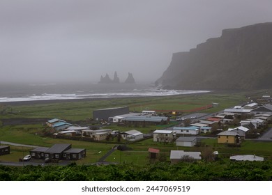 Foggy landscape of Vik i Mydral coastline in Iceland with Reynisfjara Black Sand Beach, Reynisdrangar basalt sea stacks and vertical cliffs.  - Powered by Shutterstock